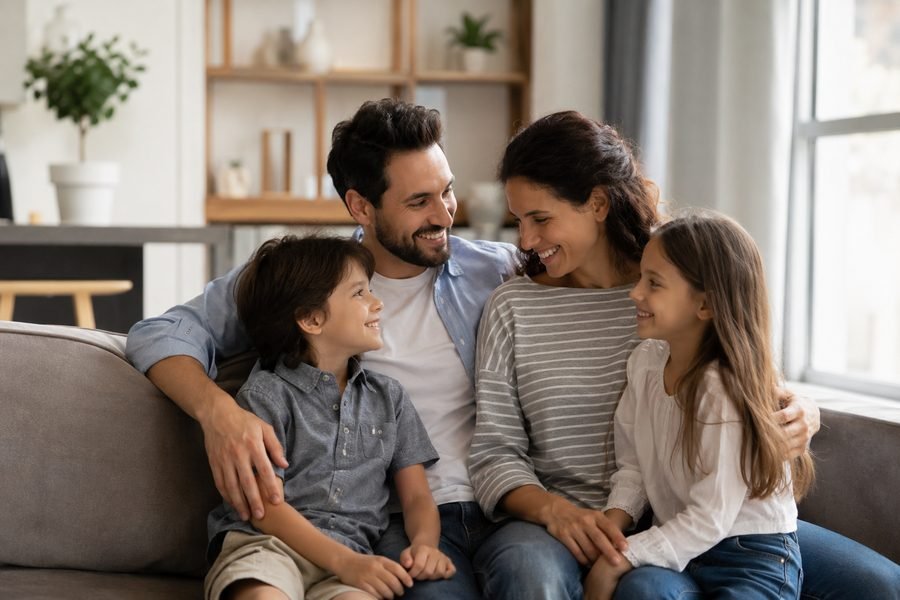 Familia sonriendo junta en la sala de su hogar